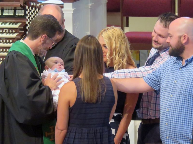 Infant baptism with pastors and parents.