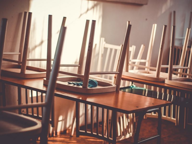 Empty classroom with chairs stacked on tables.
