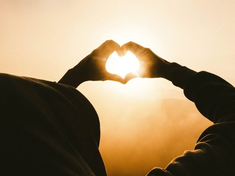 Hands forming a heart looking toward the sun.