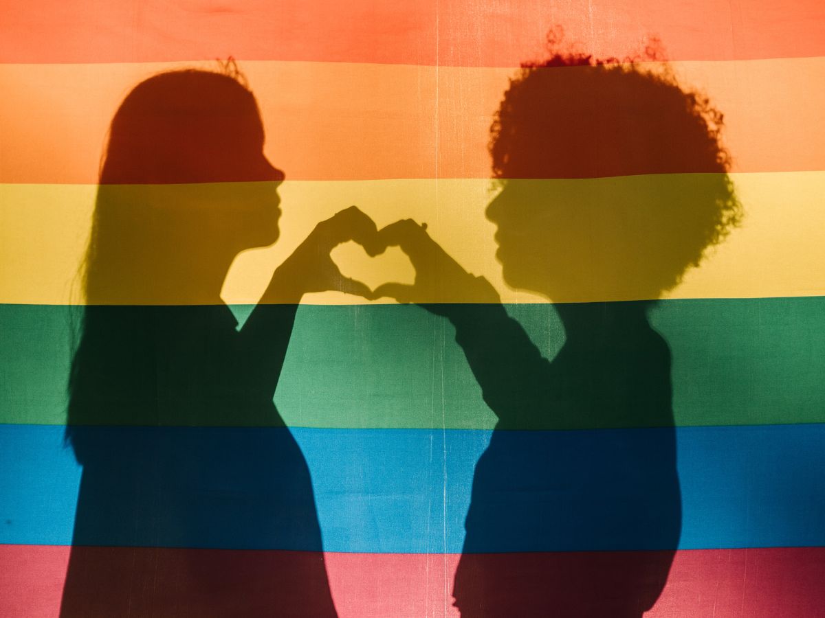 Pride flag with girls silhouette and hand heart