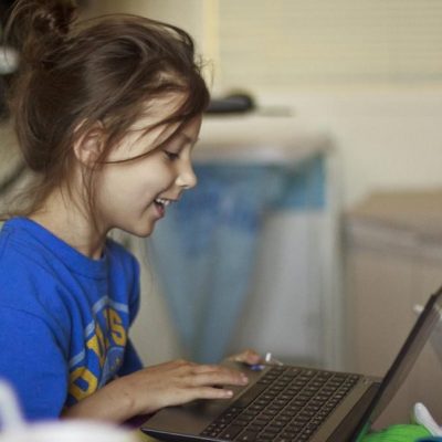 A child enjoys a Computer Rehab laptop in her hospital bed.