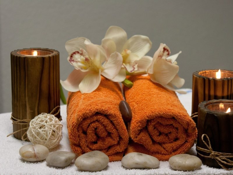 Photo of spa day towels rolled and ready with candles in the background.