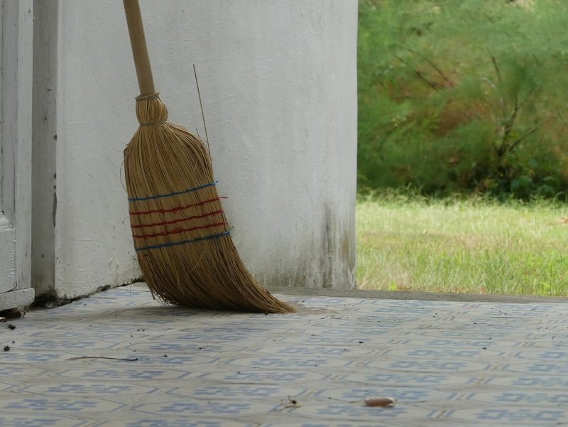Photo of a broom sitting outside on a porch ready for use.