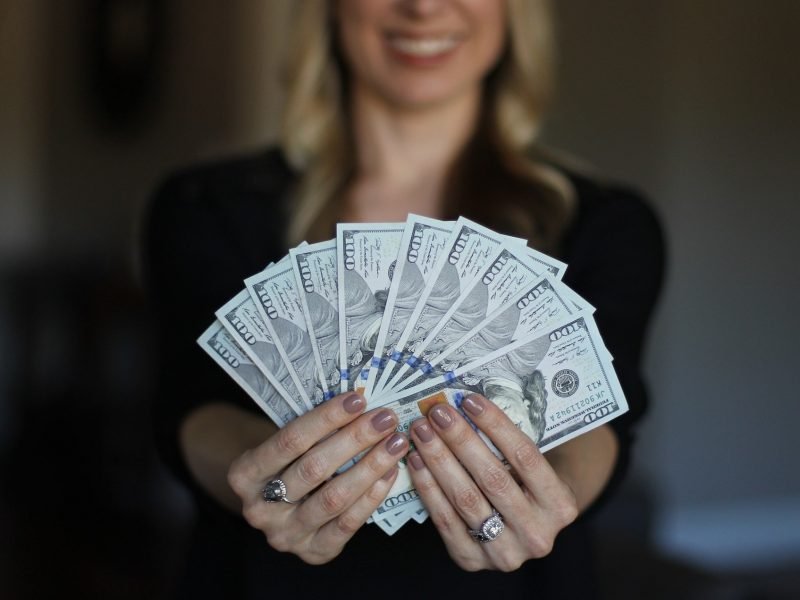 woman happily holding $100 dollar bills
